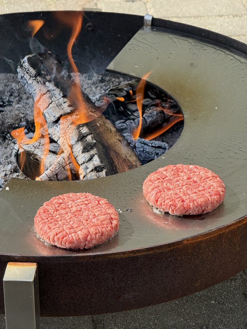 Burgeru gaļas grillēšana uz nerūsējoša tērauda gatavošanas virsmas ugunskuram